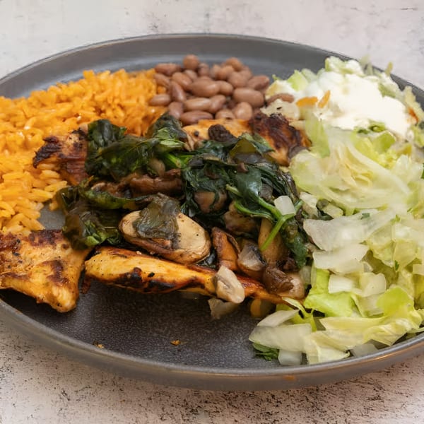 El Que Pasa's Mexican dish with grilled chicken, rice, beans, spinach, mushrooms, and salad.