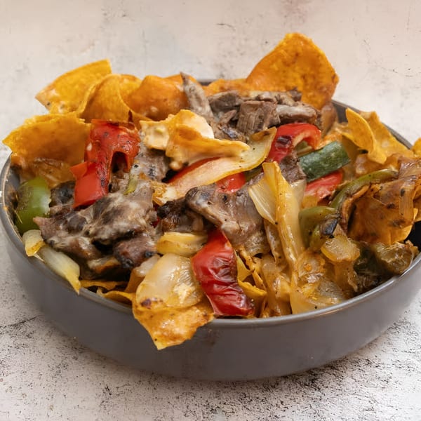 El Que Pasa's Mexican dish with meat, peppers, onions, and tortilla chips in a gray bowl.