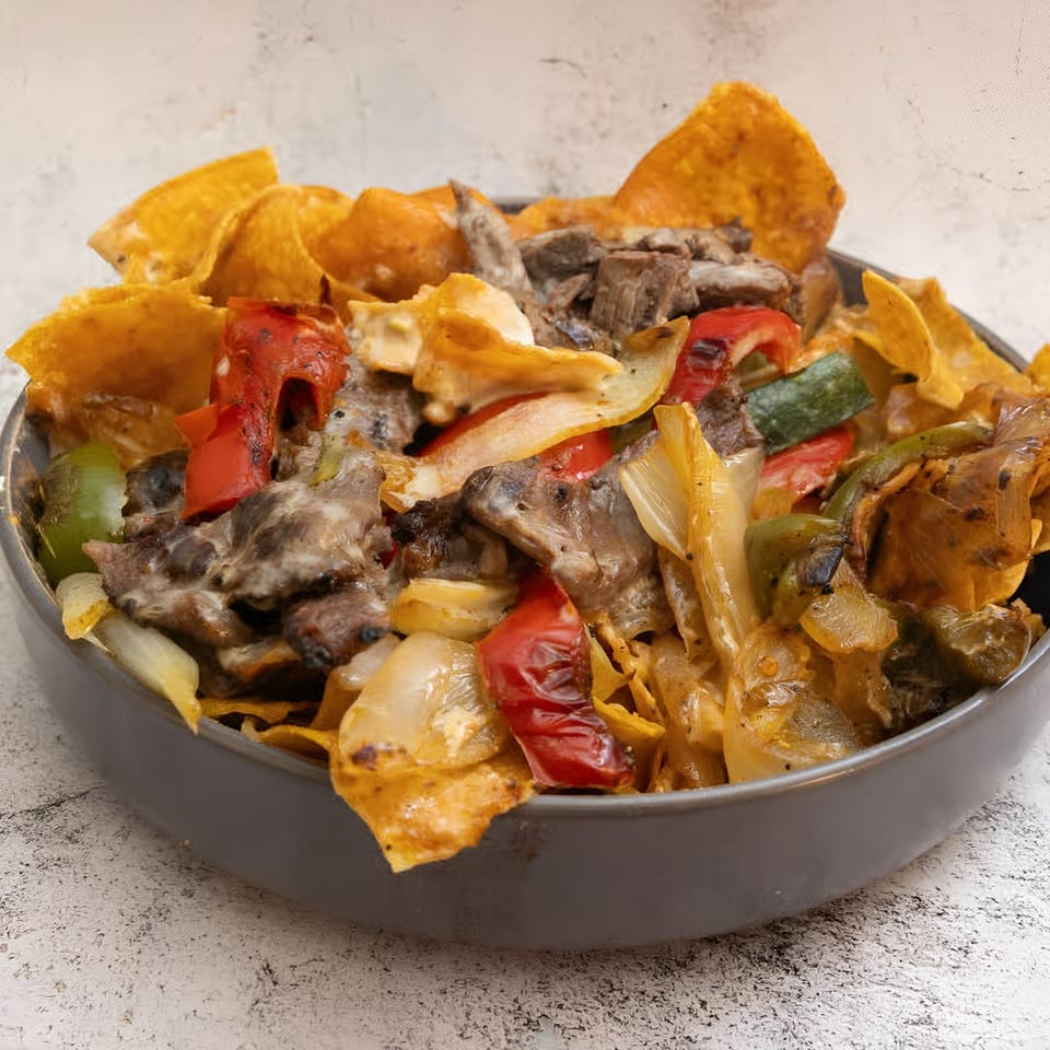 El Que Pasa's Mexican dish with meat, peppers, onions, and tortilla chips in a gray bowl.
